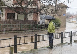 Un hombre junto a un arroyo crecido tras caer una troma de agua.