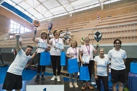 Jugadoras de pádel recogiendo su trofeo en la clausura de las escuelas de mayores, junto a sus monitores.